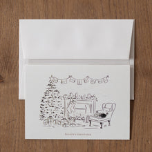 Load image into Gallery viewer, Greeting card with festive illustration of a fireplace and Christmas tree on a wooden surface
